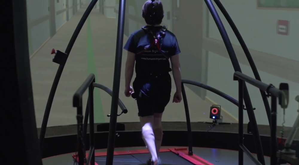 A participant walks on the treadmill in a virtual hospital hallway while the platform applies a rotation perturbation.