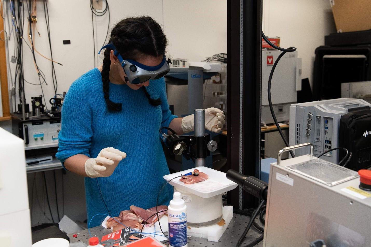 A student in a laboratory places a piece of chicken on a vibrometer. 