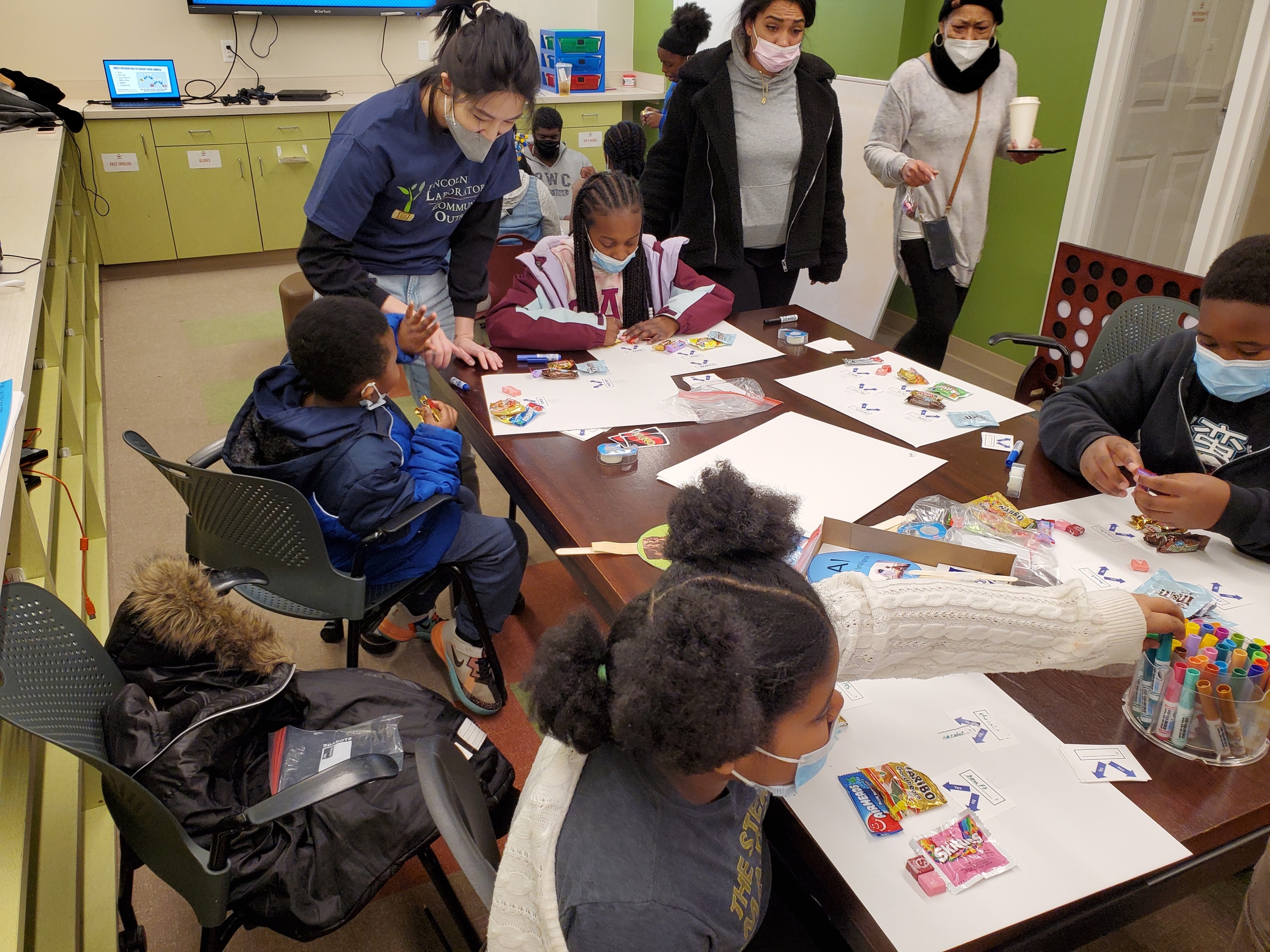 At Brookview House in April 2022, Victoria Helus (standing left) helps workshop participants with their candy decision trees.