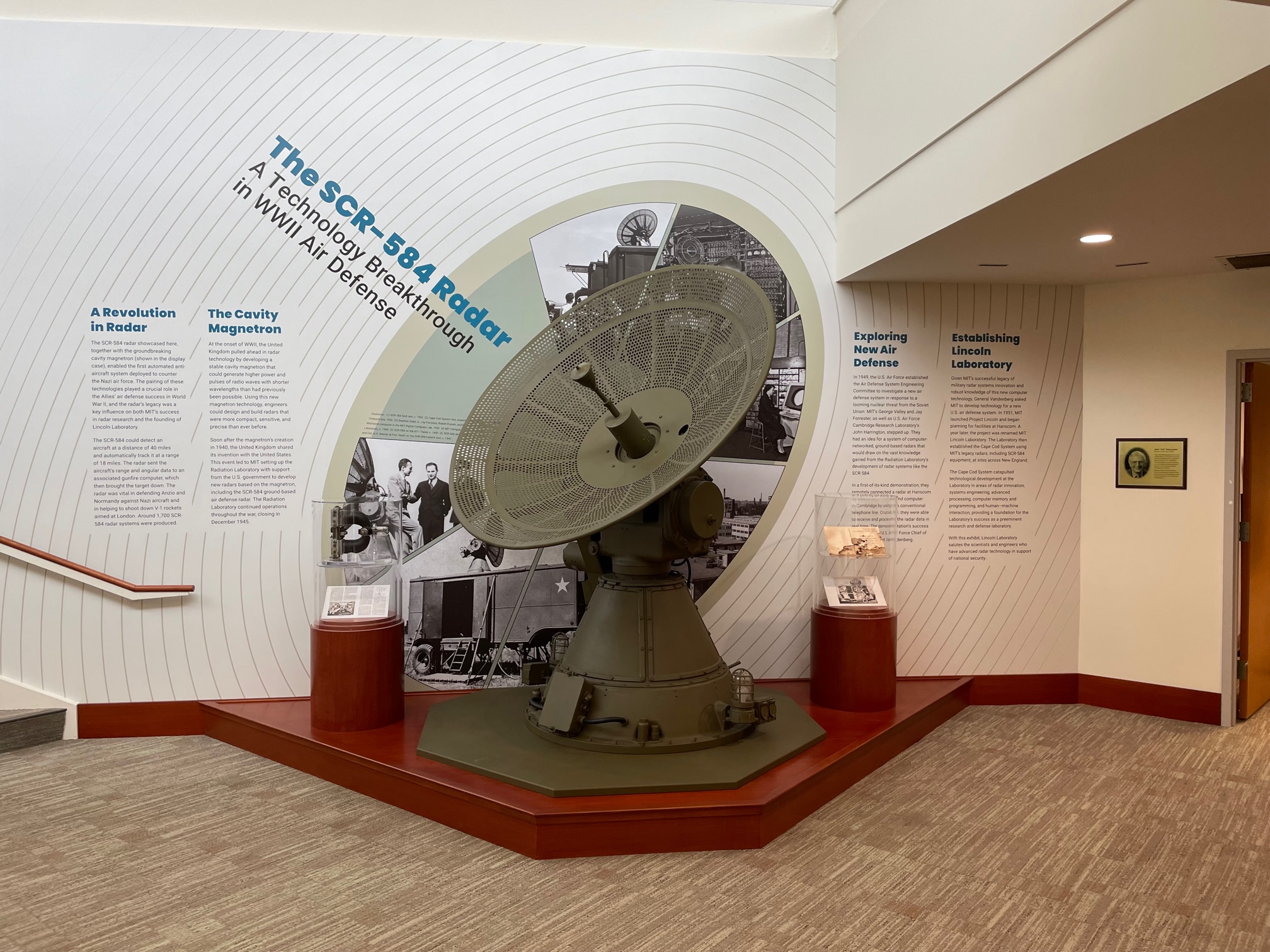 A photograph of the SCR-584 radar at Lincoln Laboratory in front of a wall of text about its development and use in World War II.