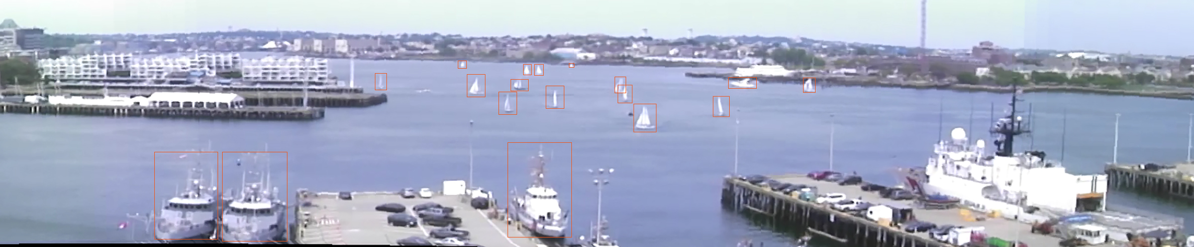 a photo of boston harbor with several boats on the water; each boat has an orange box drawn around it as a 'detection'