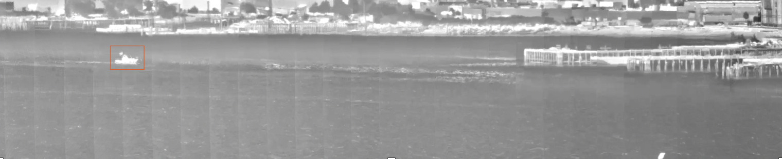 an infrared image of a boat in a harbor, with an orange box drawn around it to signify a detection. 