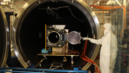 Engineers load a satellite into an ETL space simulation chamber for testing.