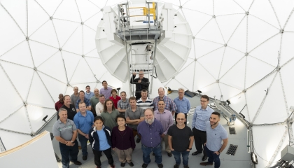 Twenty-five members part of the development team for the Multi-Band Test Terminal and Protected Anti-Jam Tactical SATCOM gather inside the antenna's radome.