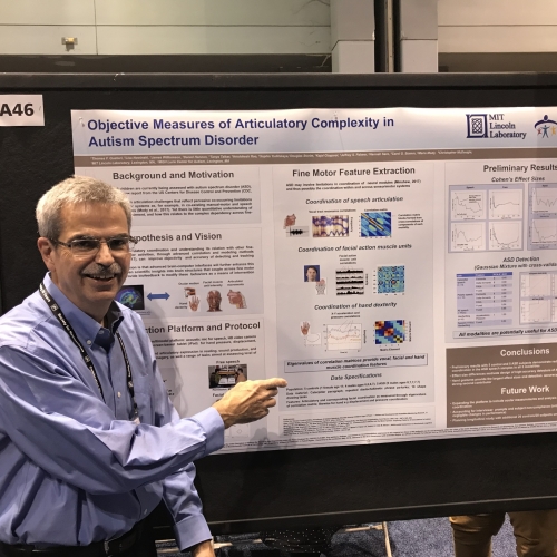 Photo of Thomas Quatieri with a poster on autism spectrum disorder in the background.