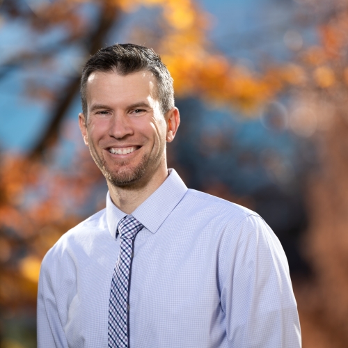 A portrait photograph of Matthew Rebholz, with a blurred fall background.