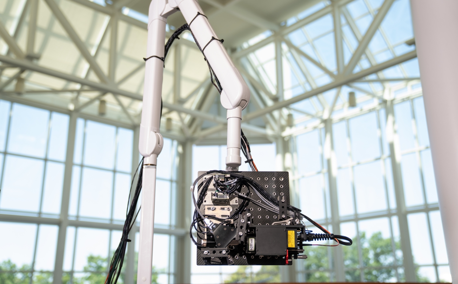 A photo of the NCLUS instrument attached to a robotic arm. 