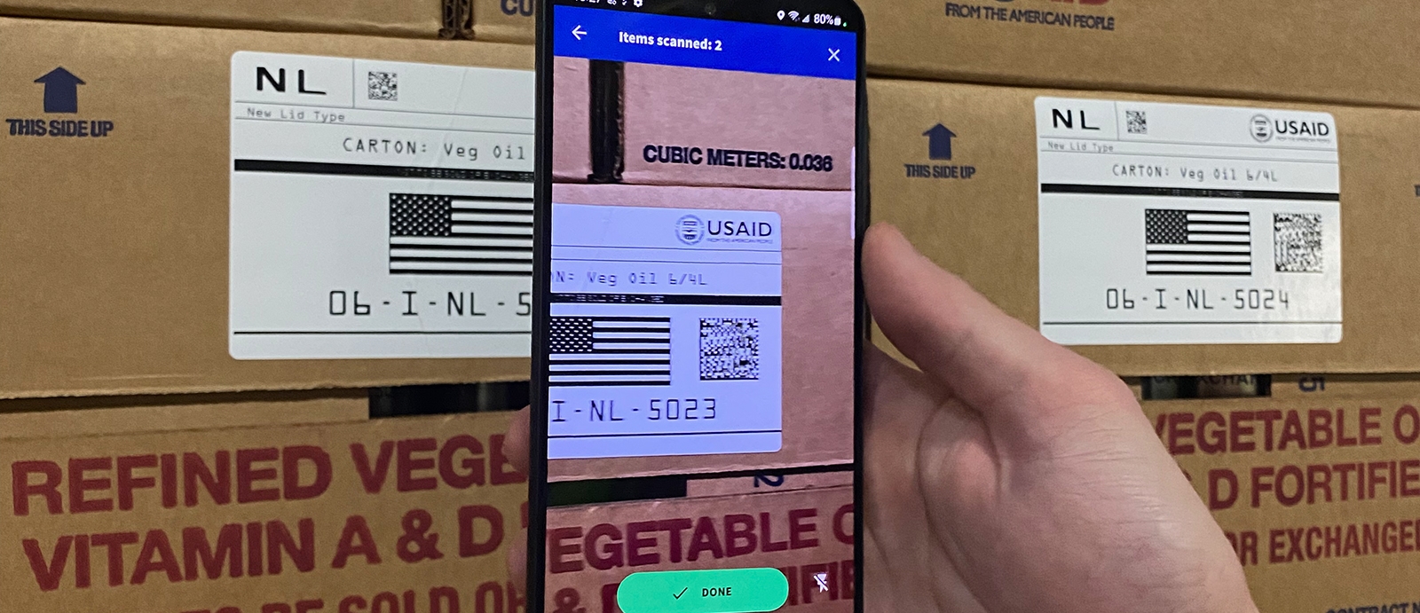 A person holds a smartphone scanner in front of a barcoded box.