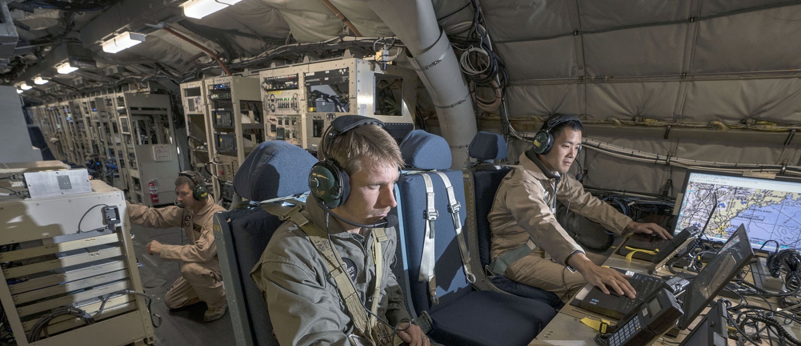 MIT Lincoln Laboratory personnel Joseph Zurkus, left, and Jacob Huang, right, operate a protected tactical waveform modem and collect data while Ted O’Connel monitors terminal equipment to ensure everything is working properly during flight testing Oct. 5