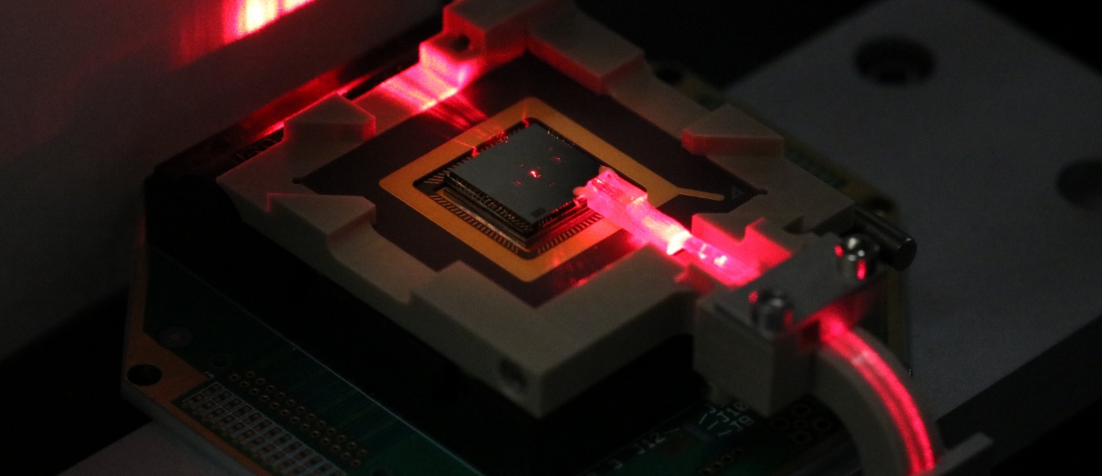 A square electronic chip with a red laser hitting the side of it