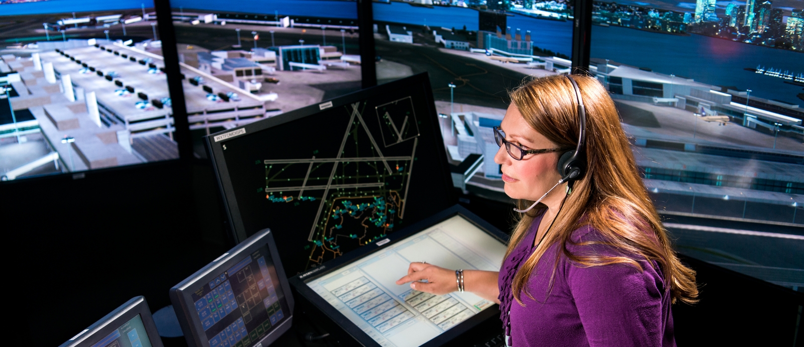 In the control tower simulation facility, an Air Traffic Control Systems staff member uses integrated electronic flight data and surveillance systems to direct an aircraft to taxi toward the runway. 