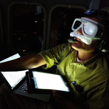 Wearing an oxygen mask inside the low-pressure cabin of the Twin Otter aircraft, Rajan Gurjar monitors the progress of the Laboratory's airborne ladar system. Photo: Brandon Call