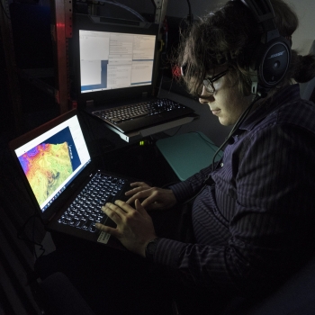 a summer research student monitors a laptop with lidar data while sitting in an airplane. 