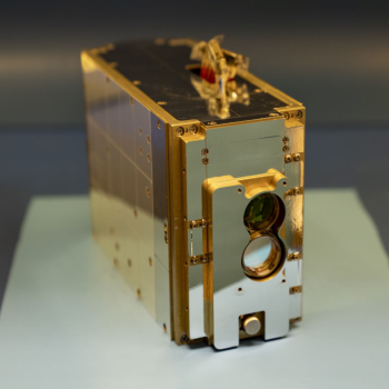 A gold rectangular box, roughly the size of a tissue box, is on display.