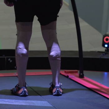 Inside the CAREN system dome, a split-belt treadmill is mounted on a six-degree-of-freedom platform that mimics the terrain of the virtual environment presented. 