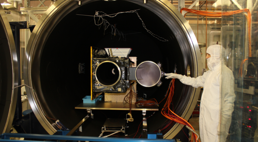 Engineers load a satellite into an ETL space simulation chamber for testing.