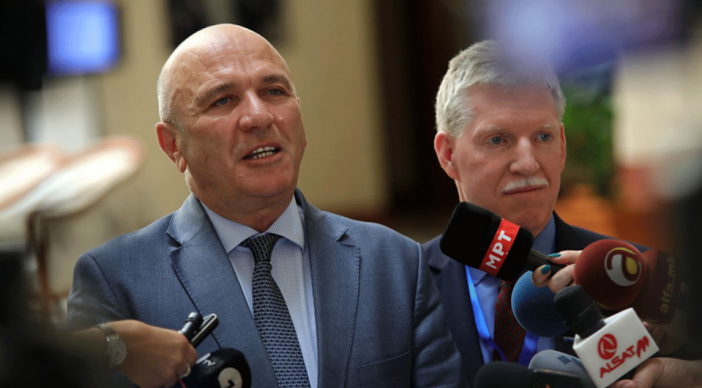 Photo of two men talking into microphones at a press conference 