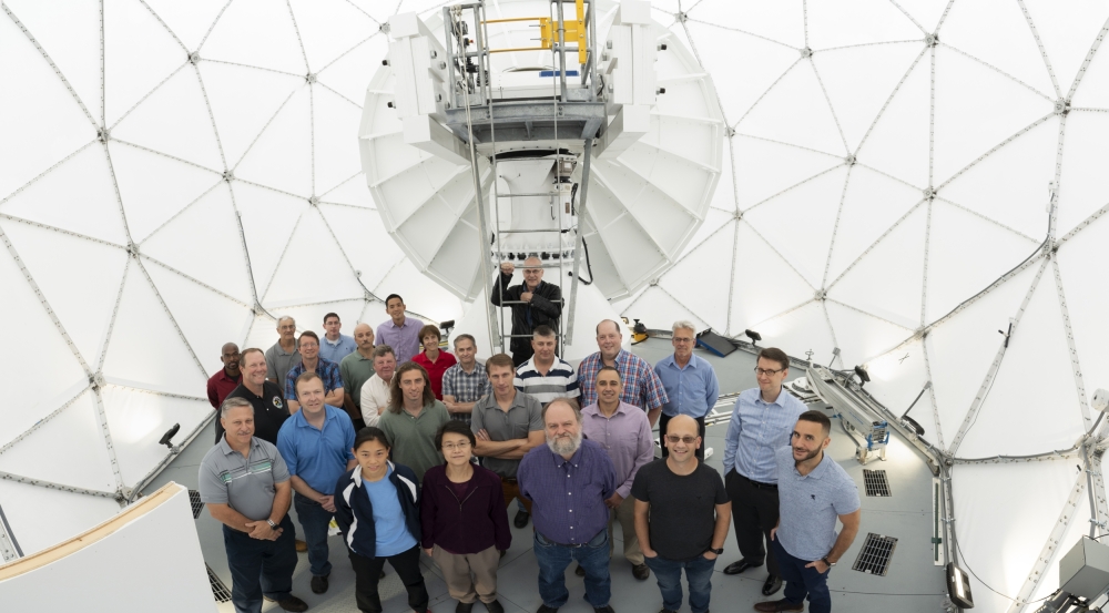 Twenty-five members part of the development team for the Multi-Band Test Terminal and Protected Anti-Jam Tactical SATCOM gather inside the antenna's radome.