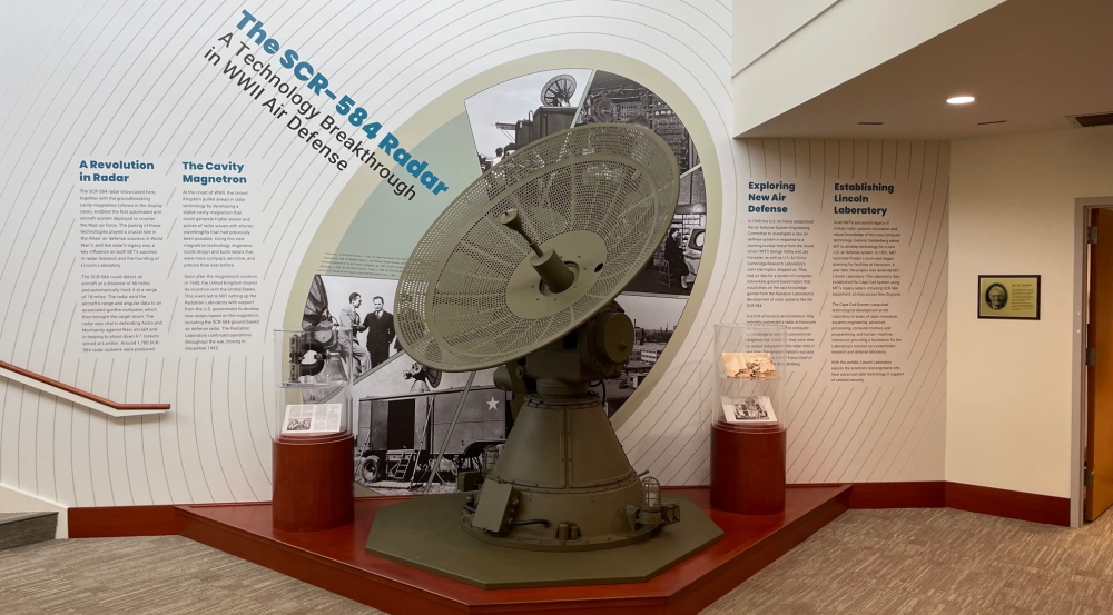 A photograph of the SCR-584 radar at Lincoln Laboratory in front of a wall of text about its development and use in World War II.