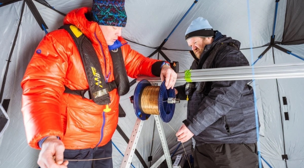 Researchers inside a tent inspect a spool with sensors.