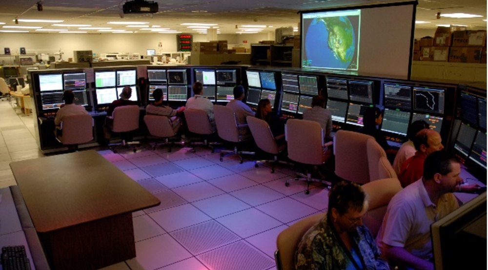 A dozen operators sit in front of computer screens. 
