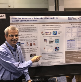 Photo of Thomas Quatieri with a poster on autism spectrum disorder in the background.