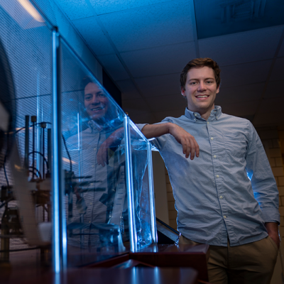 Photo of Ryan Burrow standing next to a glass display