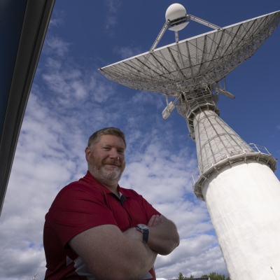 A photograph of Noah Stein standing in front of a radar. 