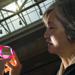 Christine Wang holds her American Association for Crystal Growth Award. The light catches the award, a synthetic ruby inset with a plaque describing the honor.