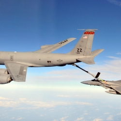 A large KC-135R tanker aircraft refuels an F-15 Eagle aircraft while they in mid air. 