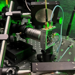 Hardware set up on a lab bench, with green laser light illuminating the background.