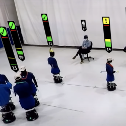 An screengrab from the video showing about a dozen robots in a large room (representing humans at a party)