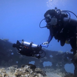 A person swimming underwater maps a sunken vessel.