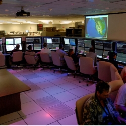 A dozen operators sit in front of computer screens. 