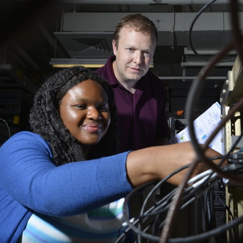 Derrick Feld looks on as AFCEA intern Chi-chi Nwodoh connects wires on the test terminal she helped build. 