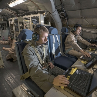 MIT Lincoln Laboratory personnel Joseph Zurkus, left, and Jacob Huang, right, operate a protected tactical waveform modem and collect data while Ted O’Connel monitors terminal equipment to ensure everything is working properly during flight testing Oct. 5