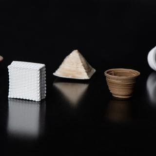 Five small 3D-printed vessels of various colors (white, browns) and shapes (cups, pyramid shapes
