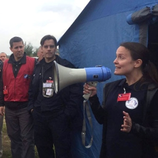 Steph Foster speaks through a megaphone to a gathering of first responders and officials.