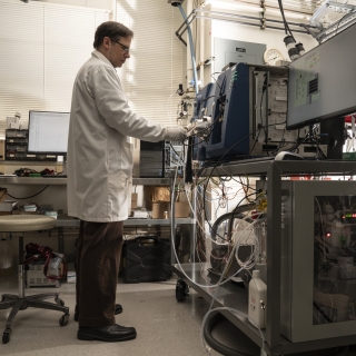 Laboratory staff member Ted Mendum stands while performing system checks on a mass spectrometer inside the laboratory. Photo: Glen Cooper