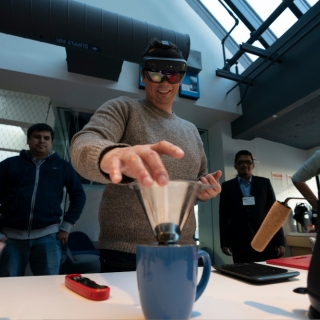 A person wearing a VR headset picks up a pour-over coffee filter.