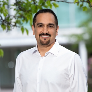 Hamed Okhravi smiles for a photo, standing outside with the front entrance displaying "Lincoln Laboratory" in the background.