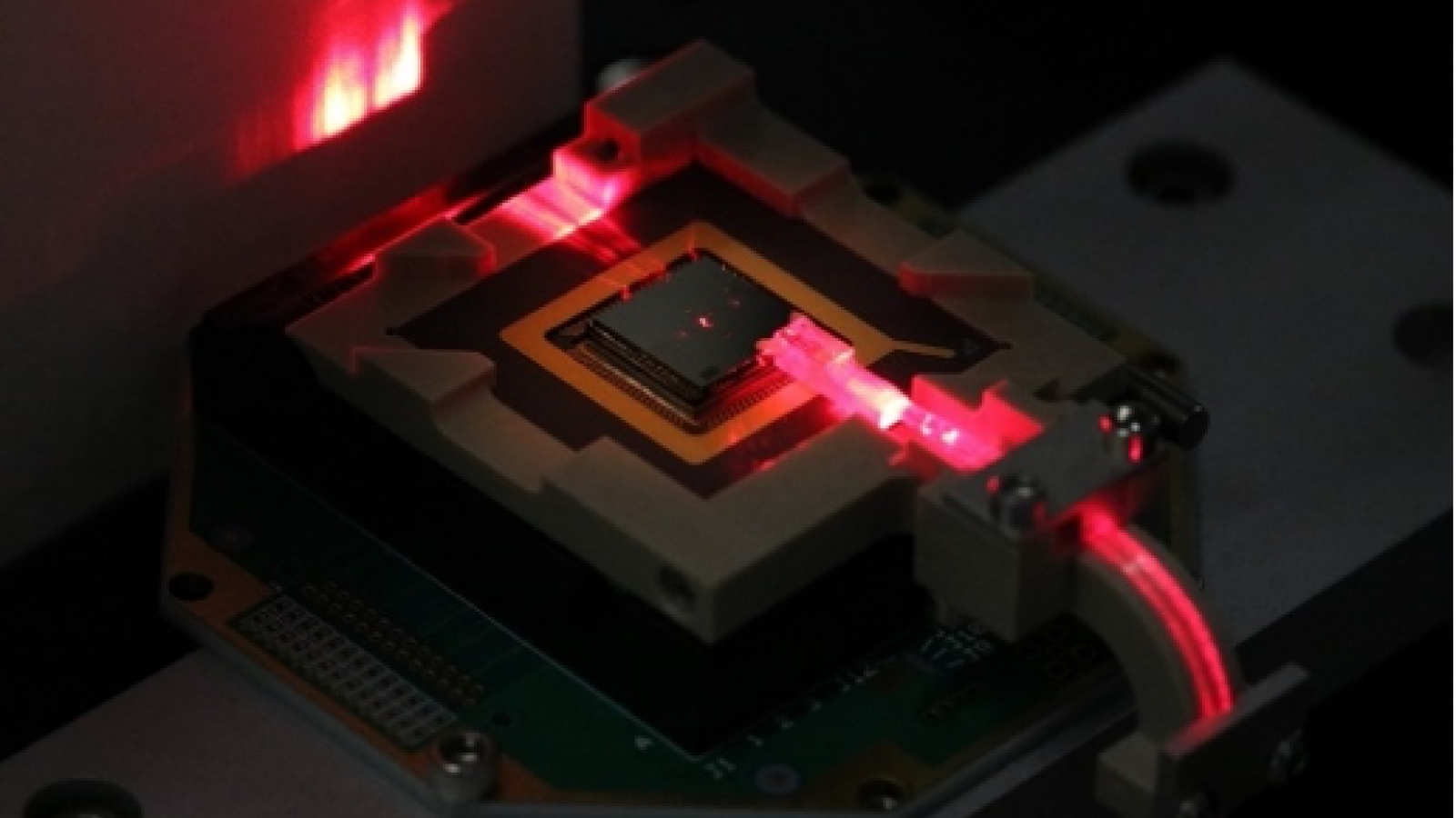 a small electronic chip is illuminated with red laser light. 