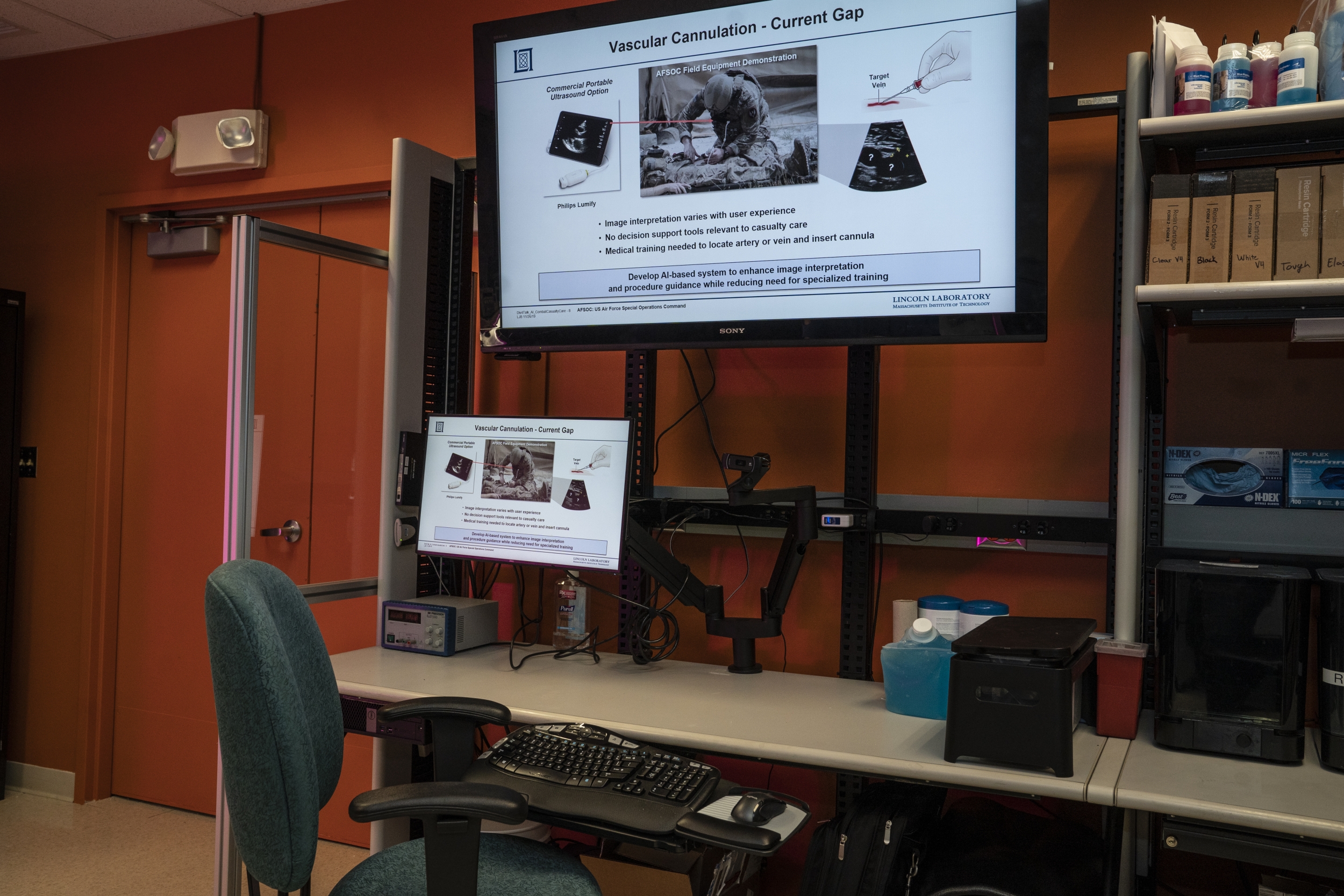 A desk with a small monitor and large TV screen monitor. 