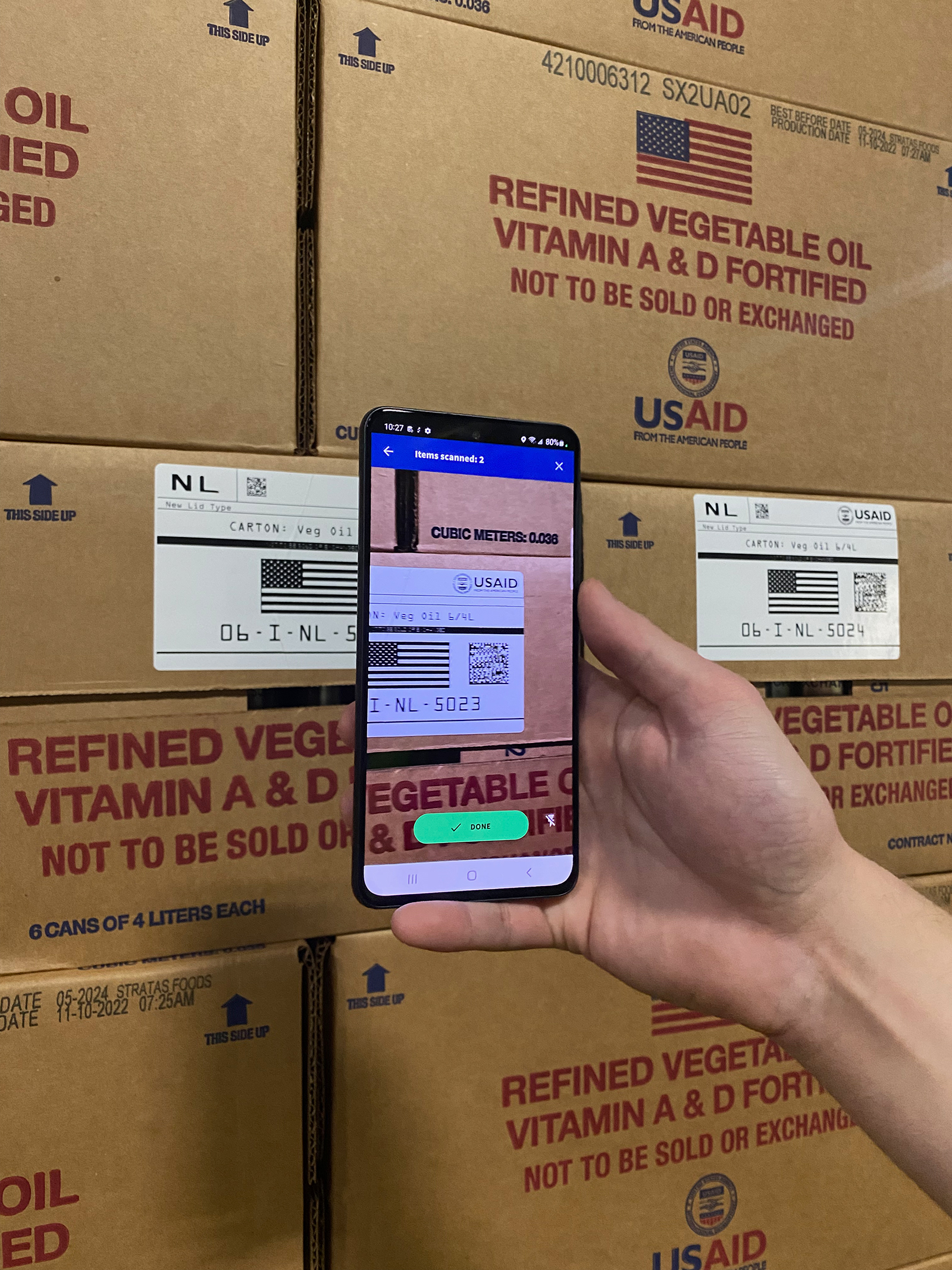 A person holds a smartphone scanner in front of a barcoded box.