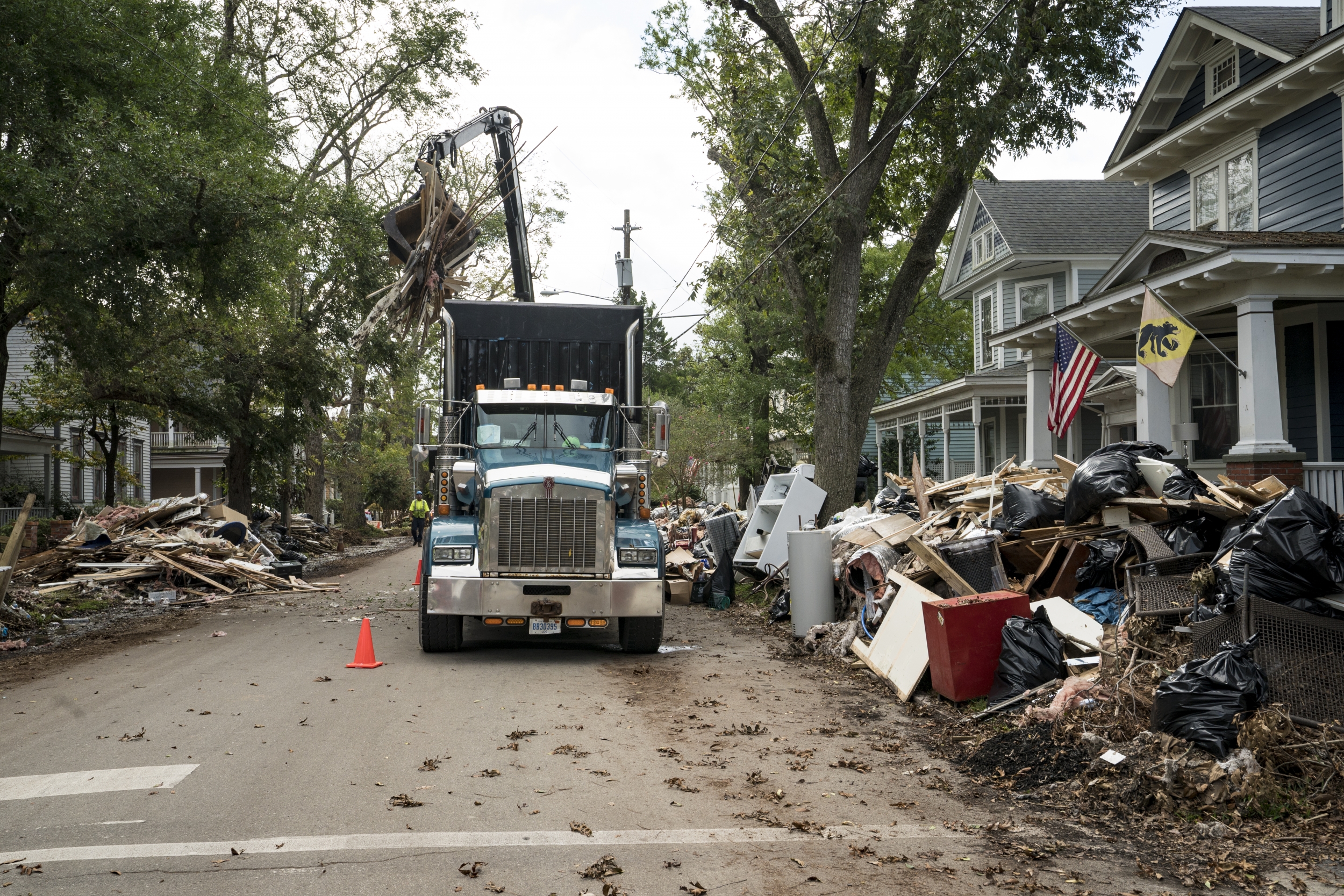 A photo of a large truck picking up debris lining a street