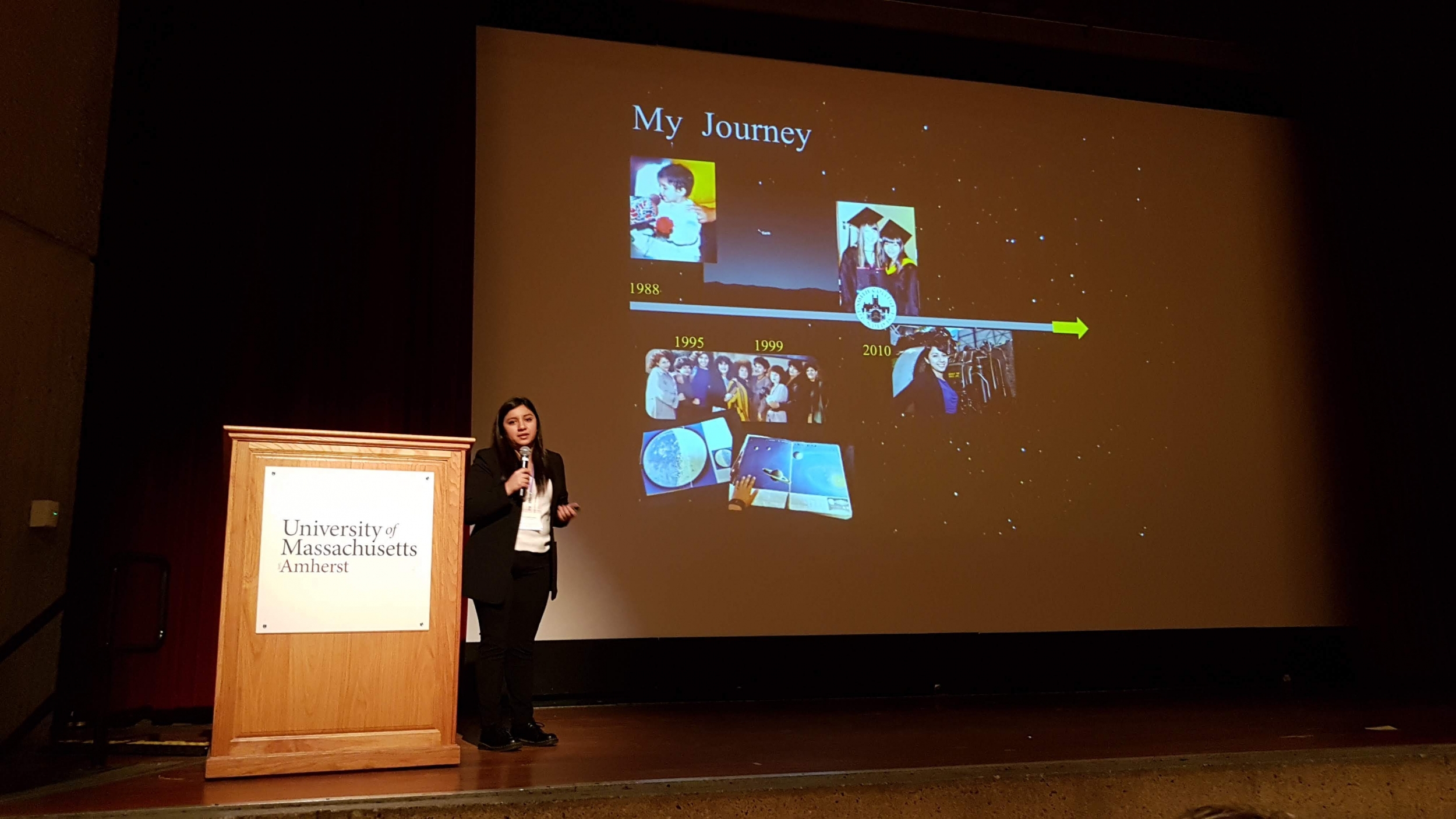 Yari Golden-Castano stands on stage in front of a slide titled "My Journey" as she gives a plenary talk.