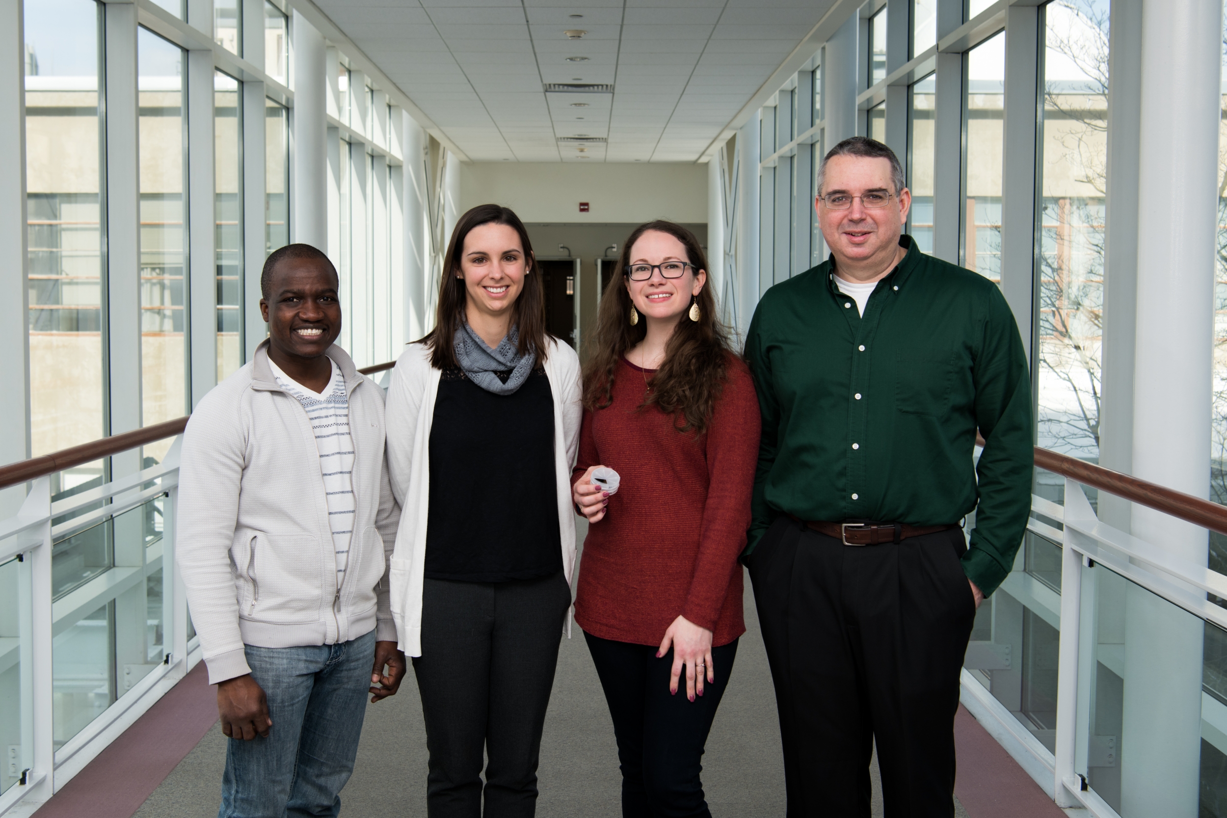 The team of four researchers pose for a group photo in a hallway