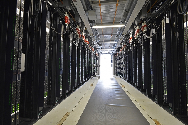 Interior of the supercomputing EcoPOD showing server racks on either side of a hallway.