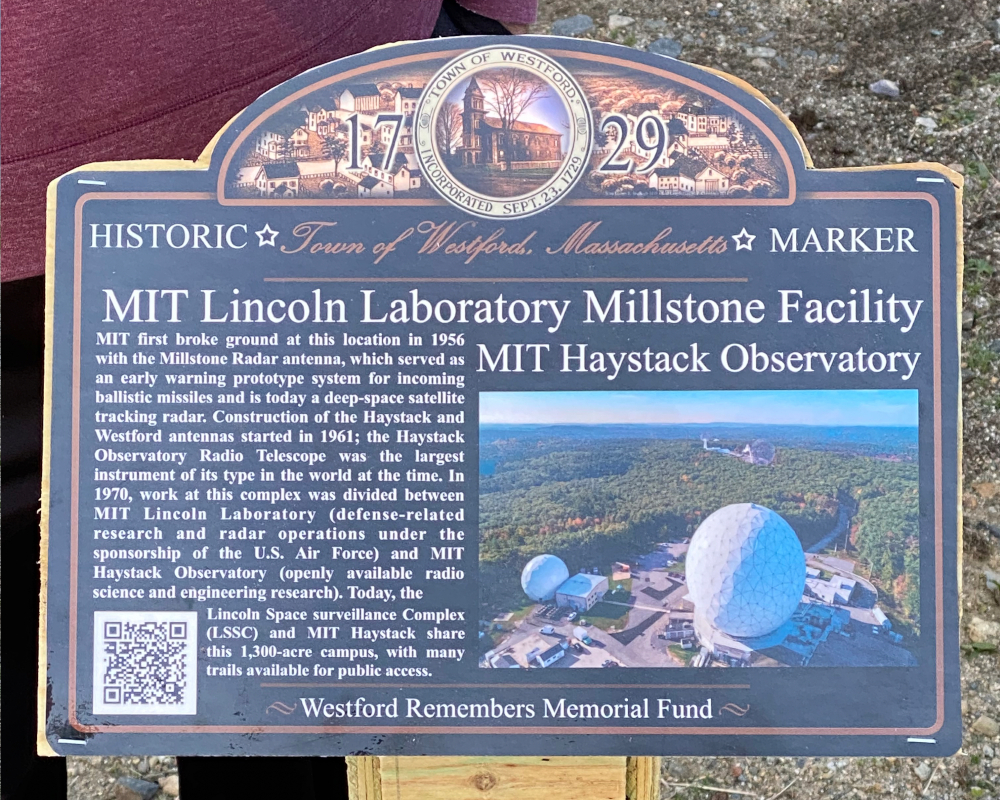 A close up view of the sign Scout Carter Purple created about Millstone and Haystack. The sign is blue with white writing, contains a photo of Haystack, and a QR code.