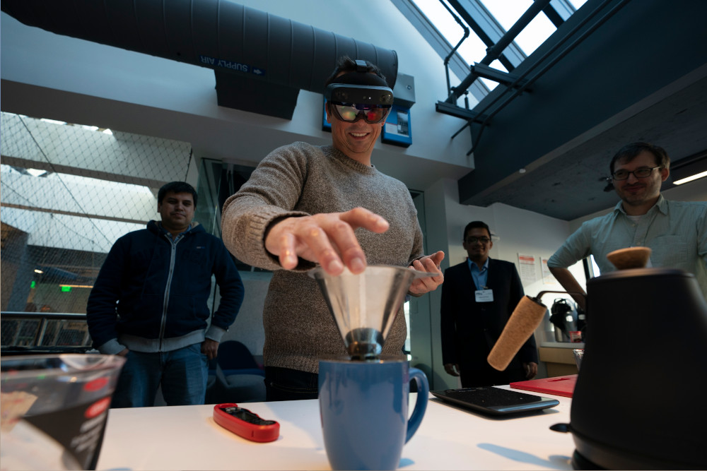 A person wearing a VR headset picks up a pour-over coffee filter.